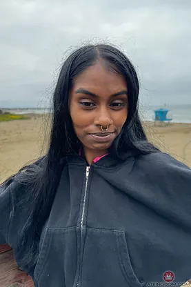 Watch petite Indian babe Fae Love tease and flash her clean-shaven pussy up close on the beach