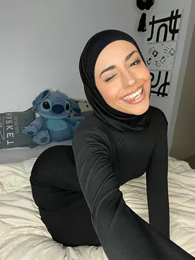 Watch her switch between hijab and lingerie while getting off in solo action on the couch